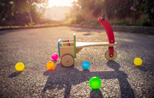 Child's bicycle on playground, vintage colorful wooden childish bicycle and colorful balls outdoors in sunny summer day