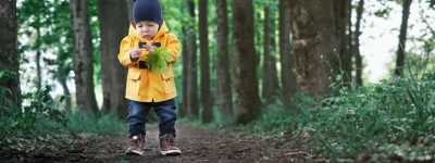 Small boy in yellow jacket in summer park